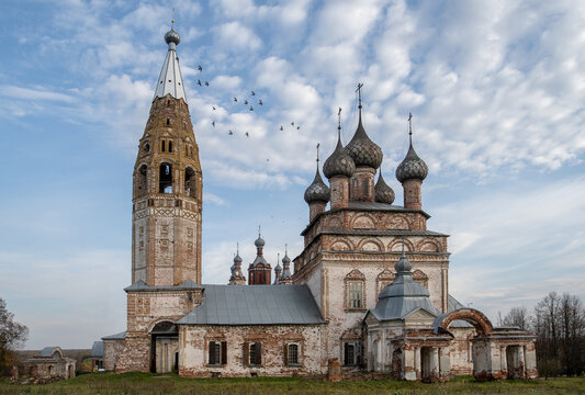 An old rural temple in need of restoration. A flock of birds above the domes.