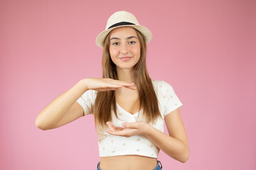 Happy young woman standing isolated over pink wall background. Looking camera showing copy space pointing.
