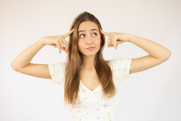 Fototapeta premium Young beautiful woman over isolated white background and thinking with two fingers on her head very concentrated.