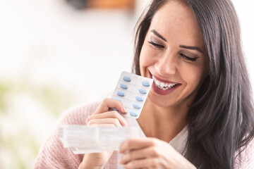 Woman reading a label of pills packaging, smiling