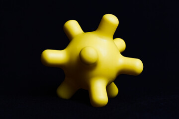 Yellow colorful bright isolated spiky ball toy on a black background, macro