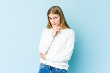 Young blonde woman isolated on blue background contemplating, planning a strategy, thinking about the way of a business.