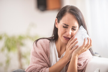 An effort of a girl to ease aching tooth by a bag of ice at home