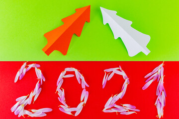 Obraz premium Inscription 2021 with petals on a red green background. New Year decoration with christmas tree and flower petals. Nature concept
