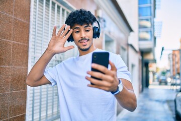 Fototapeta na wymiar Young arab man smiling happy doing video call using smartphone walking at city.