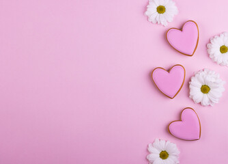 pink gingerbread hearts with white flowers on a pastel pink background. background for Valentine's day, mother's day