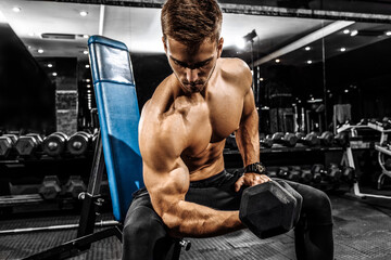 strong muscular man with a naked torso trains with kettlebells in the gym