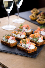 Christmas tapas with salmon and crème cheese with dill and white wine glasses, New year celebration, toasts for party dinner