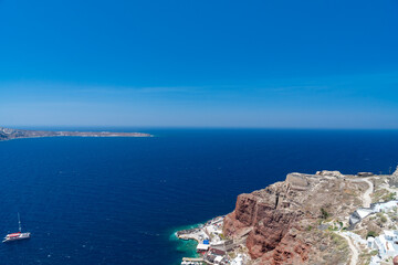 Fototapeta na wymiar Panoramic view from white building, blue sky and vivid sea, cliffs in Santorini island, Oia, Greece. 