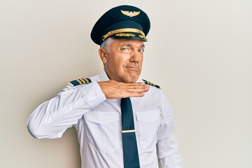 Handsome middle age mature man wearing airplane pilot uniform cutting throat with hand as knife,...