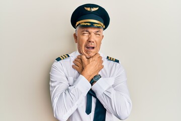Handsome middle age mature man wearing airplane pilot uniform shouting suffocate because painful strangle. health problem. asphyxiate and suicide concept.