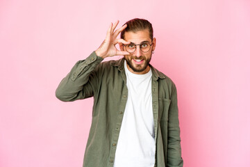 Young man with long hair look excited keeping ok gesture on eye.