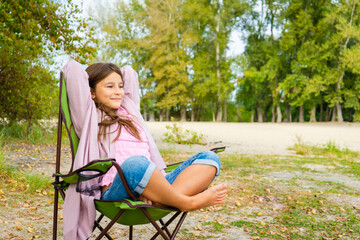 Little adorable girl relaxed and happy, sitting on a folding chair for travel