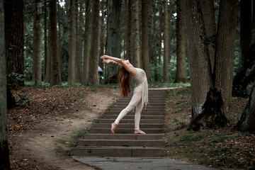 Young woman with long hair dancing in nature in summer on concrete steps. Clothing made of eco-friendly materials in beige and macrame.