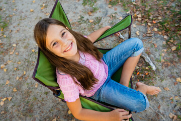 Little adorable girl relaxed and happy, sitting on a folding chair for travel