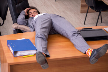 Young male employee sleeping at workplace