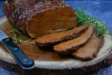 Vegan seitan roast rubbed with spices and bbq sauce on wooden board, sliced, copy space