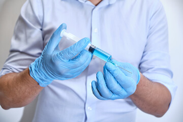 Pandemic concept, close up of scientist injecitng vaccine. Doctor, nurse, scientist hand in blue gloves holding flu, measles, coronavirus, covid-19 vaccine disease preparing for people.