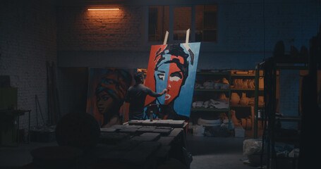 Anonymous artist painting portrait in dark studio