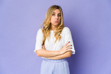 Young caucasian blonde woman shrugs shoulders and open eyes confused.