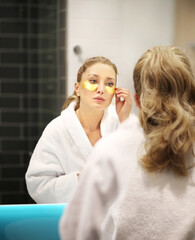 Anti-aging eye therapy. Woman taking care of his undereye wrinkles applying facial mask. Dark...