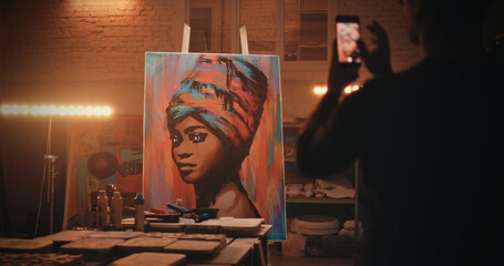 Unrecognizable artisan taking picture of portrait behind workbench