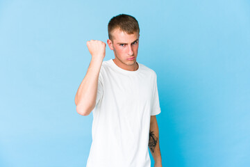 Young caucasian handsome man showing fist to camera, aggressive facial expression.