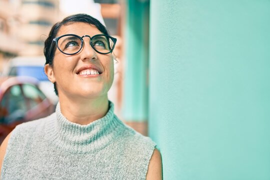 Young plus size woman smiling happy leaning on the wall at the city.