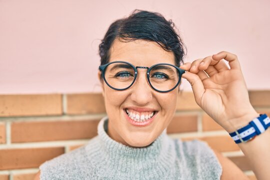 Young plus size woman smiling happy leaning on the wall at the city.
