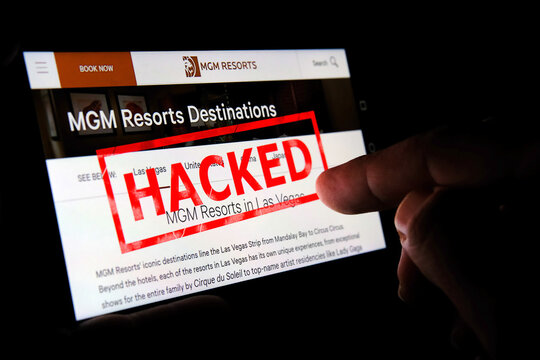 MGM website on the smartphone screen with a red stamp HACKED on top and finger pointing at it. Concept. Editorial illustrative.