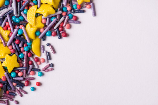 Closeup top flatlay photo of tasty colorful sugar sprinkles in corner of picture with white copy space