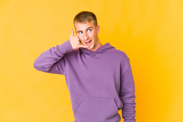 Young caucasian handsome man showing a mobile phone call gesture with fingers.