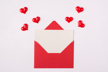 Photo of red open envelope with clear letter inside and falling flying hearts around isolated white background
