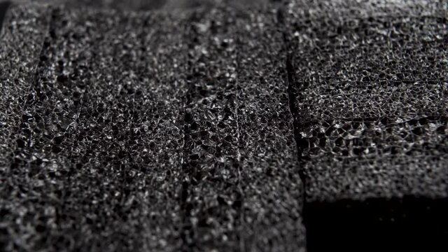 Black porous foam for packaging and shipping fragile items and electronics. Layered glued material. Macro. Dolly Shot. Close up