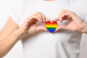 LGBT relationship concept. The girl holds a heart in the form of the flag of LGBT on her chest.