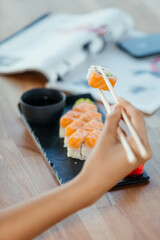 Hand holds sushi with wooden sticks. High quality photo