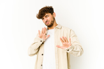 Young arab man on white background rejecting someone showing a gesture of disgust.