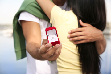 Man with engagement ring making proposal to his girlfriend near river, closeup