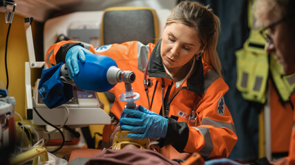 EMS Paramedics Team Provide Medical Help to Injured Patient on the Way to Hospital. Emergency Care Assistants Using a Defibrillator and Ventilation Mask to Bring the Man Back to Life in an Ambulance. © Gorodenkoff