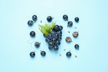 Bunch of ripe grapes with green leaves on light blue background, flat lay