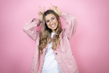 Young beautiful blonde woman with long hair standing over pink background Posing funny and crazy with fingers on head as bunny ears, smiling cheerful