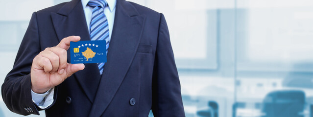 Cropped image of businessman holding plastic credit card with printed flag of Kosovo. Background...