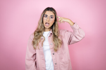 Fototapeta premium Young beautiful blonde woman with long hair standing over pink background smiling and thinking with her fingers on her head that she has an idea.