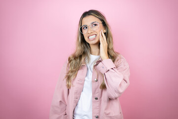 Young beautiful blonde woman with long hair standing over pink background touching mouth with hand with painful expression because of toothache or dental illness on teeth