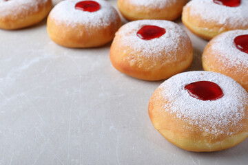 Hanukkah doughnuts with jelly and sugar powder on grey table, space for text