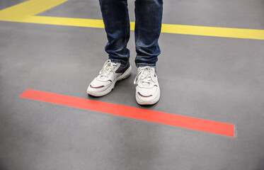 Person standing behind taped floor marking indoors for social distance, closeup. Preventive measure...