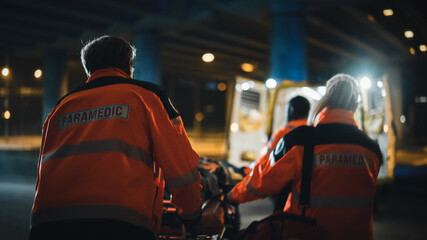 Team of EMS Paramedics React Quick to Provide Medical Help to Injured Patient and Get Him in Ambulance on a Stretcher. Emergency Care Assistants Arrived on the Scene of a Traffic Accident on a Street. - obrazy, fototapety, plakaty