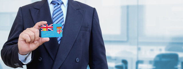 Cropped image of businessman holding plastic credit card with printed flag of Fiji. Background...