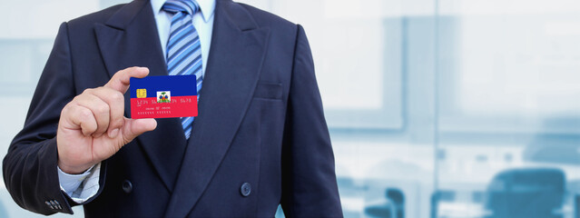 Cropped image of businessman holding plastic credit card with printed flag of Haiti. Background...