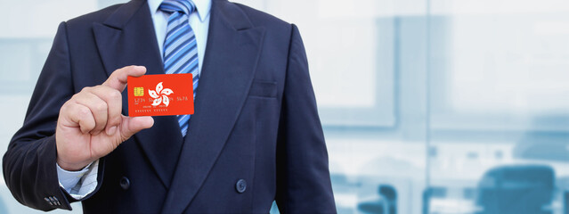 Cropped image of businessman holding plastic credit card with printed flag of Hong Kong. Background...